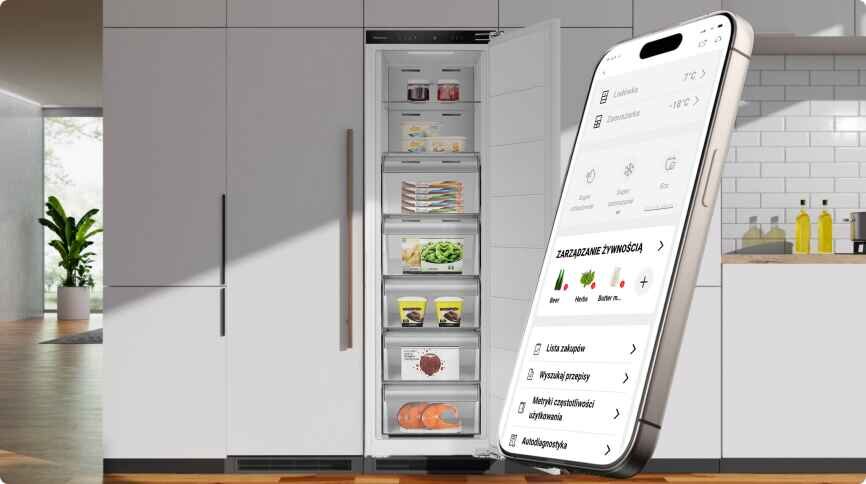 Obraz przedstawia otwartą zamrażarkę z kilkoma półkami wypełnionymi produktami spożywczymi oraz smartfon z aplikacją do zarządzania żywnością. W tle widoczna jest nowoczesna kuchnia z białymi szafkami i blatem.
