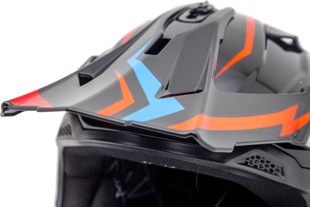 Kask motocyklowy w kolorze czarno-niebieskim z czerwonymi i niebieskimi wzorami. Widoczna jest część daszka oraz otwory wentylacyjne.