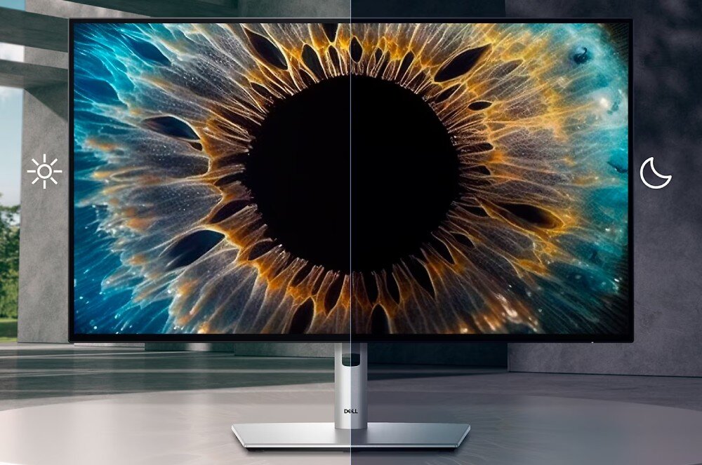Monitor z logo DELL wyświetla obraz przypominający zbliżenie na tęczówkę oka, z podziałem na jasną i ciemną stronę. Obok monitora znajdują się symbole słońca i księżyca.