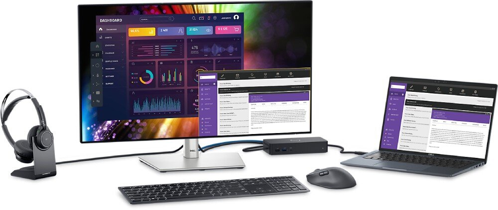 Na obrazie znajduje się zestaw komputerowy składający się z monitora, laptopa, klawiatury, myszy i słuchawek. Monitor wyświetla kolorowy interfejs z wykresami i danymi, a laptop pokazuje podobny interfejs z tekstem i tabelami.