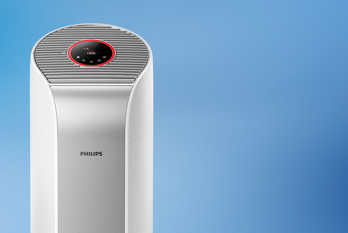 Na obrazie widoczny jest biały oczyszczacz powietrza z logo PHILIPS na przodzie. Na górze urządzenia znajduje się okrągły panel sterowania z wyświetlaczem i czerwonym obramowaniem.
