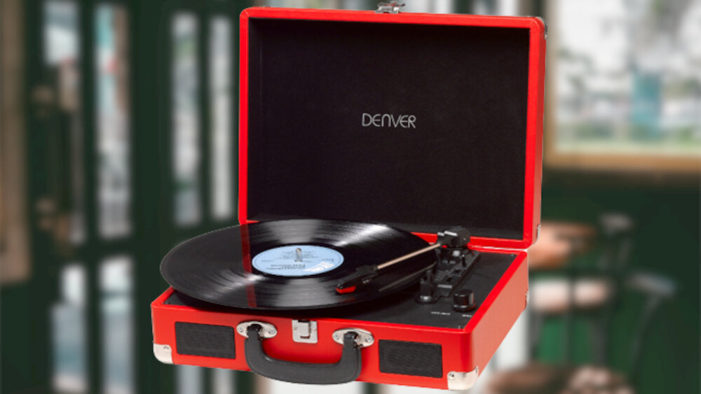 Czerwony gramofon w stylu walizki z otwartą pokrywą, na której widnieje napis \'DENVER\'. Na gramofonie znajduje się czarna płyta winylowa.