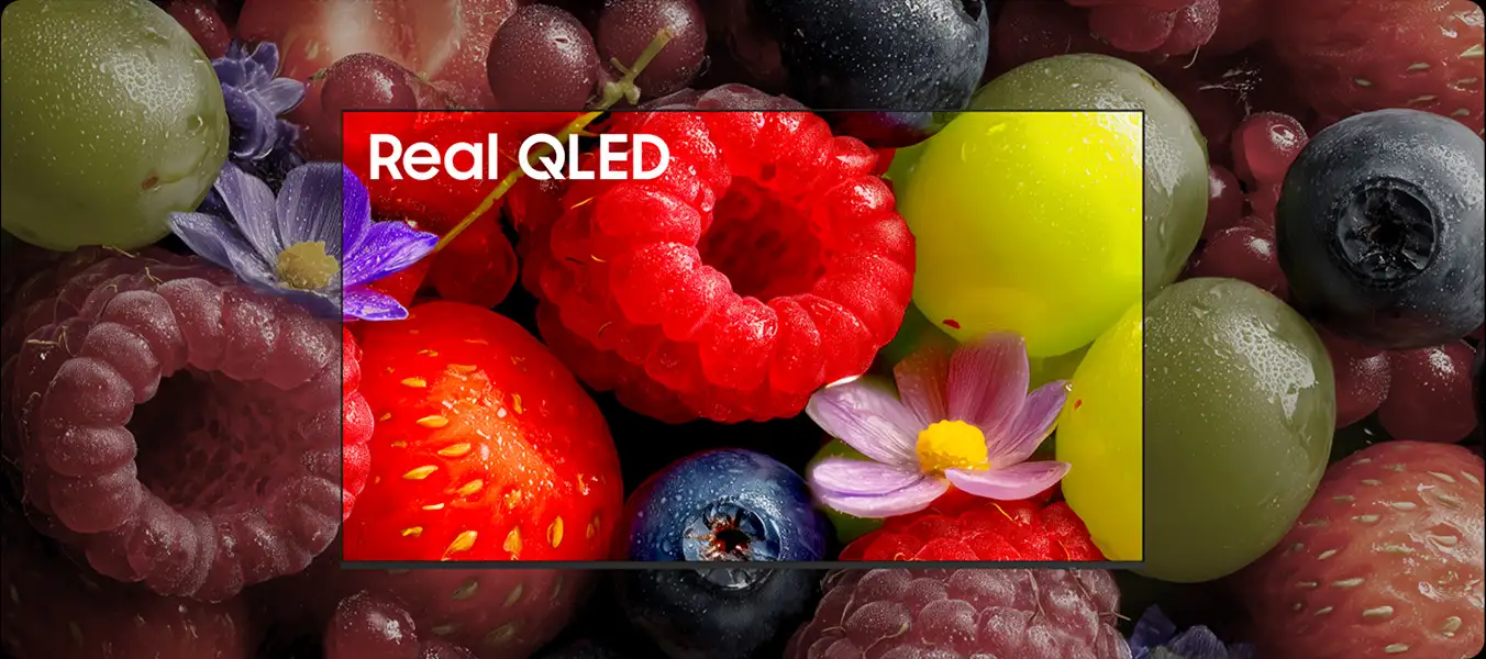 2026-neo-qled-real-qled-with-100-color-volume-pc 1352x600 Obraz przedstawia zbliżenie na różnorodne owoce, takie jak maliny, truskawki, winogrona i jagody, z widocznymi kroplami wody. Na ekranie telewizora widoczny jest napis \'Real QLED\'.