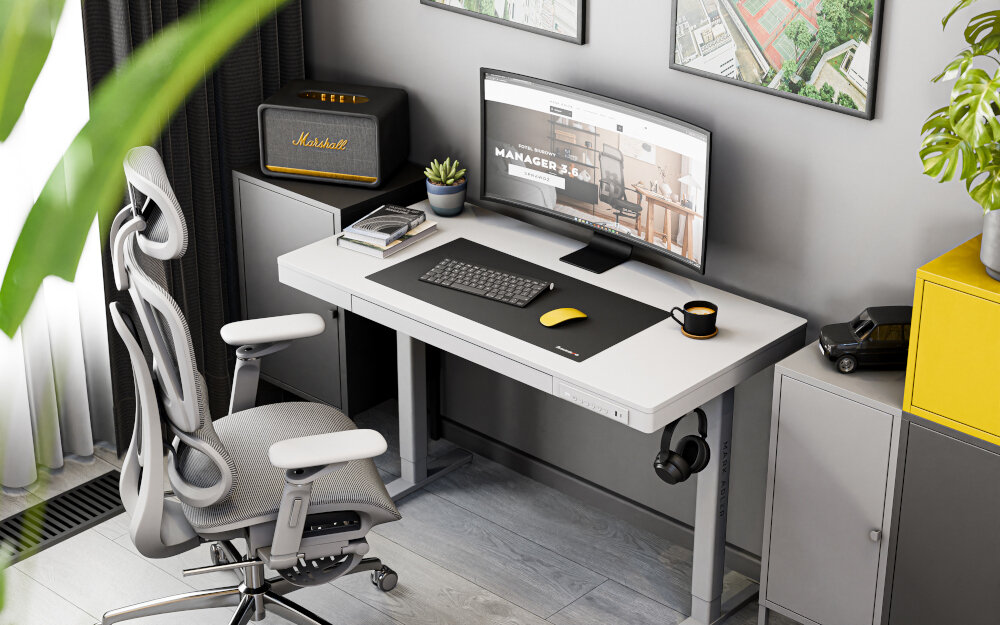 Na obrazie znajduje się nowoczesne biurko z białym blatem, na którym stoi monitor, klawiatura, myszka i kubek. Obok biurka znajduje się ergonomiczne krzesło, a w tle widoczne są szafki i dekoracje ścienne.