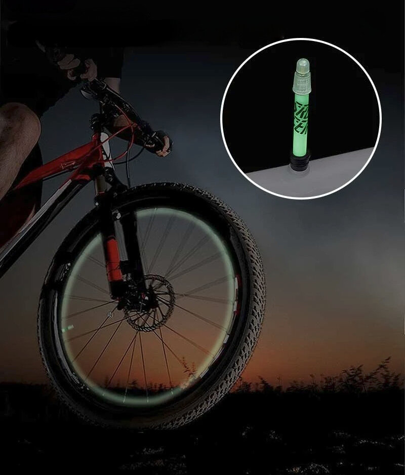 Obraz przedstawia rower górski z oświetlonym fluorescencyjnie kołem na tle zachodzącego słońca. W prawym górnym rogu znajduje się zbliżenie na fluorescencyjny wentyl Presta.
