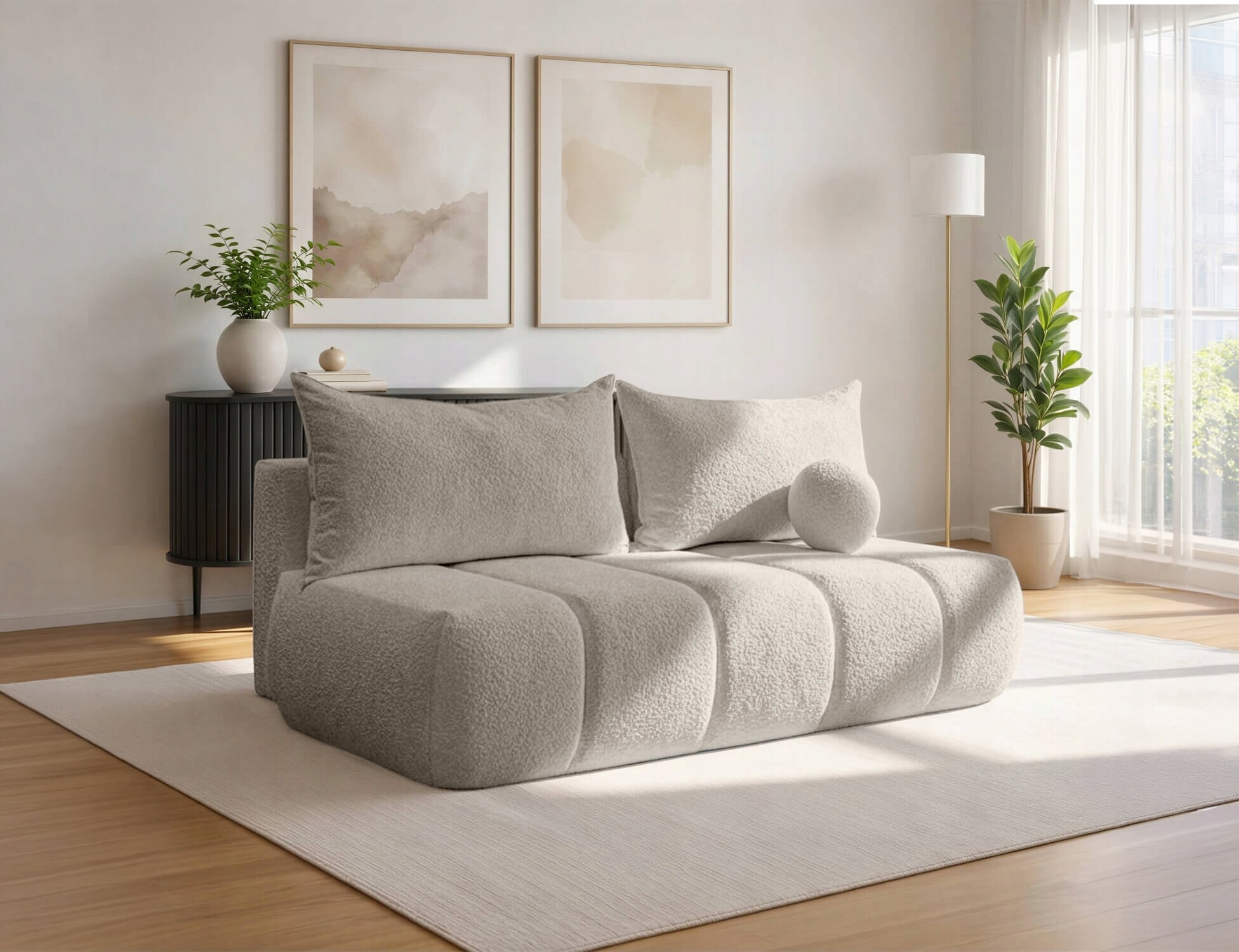 Kremowa sofa rozkładana z funkcją spania znajduje się w jasnym salonie z dużym oknem. W tle widoczne są dwa obrazy, roślina doniczkowa i lampa stojąca.