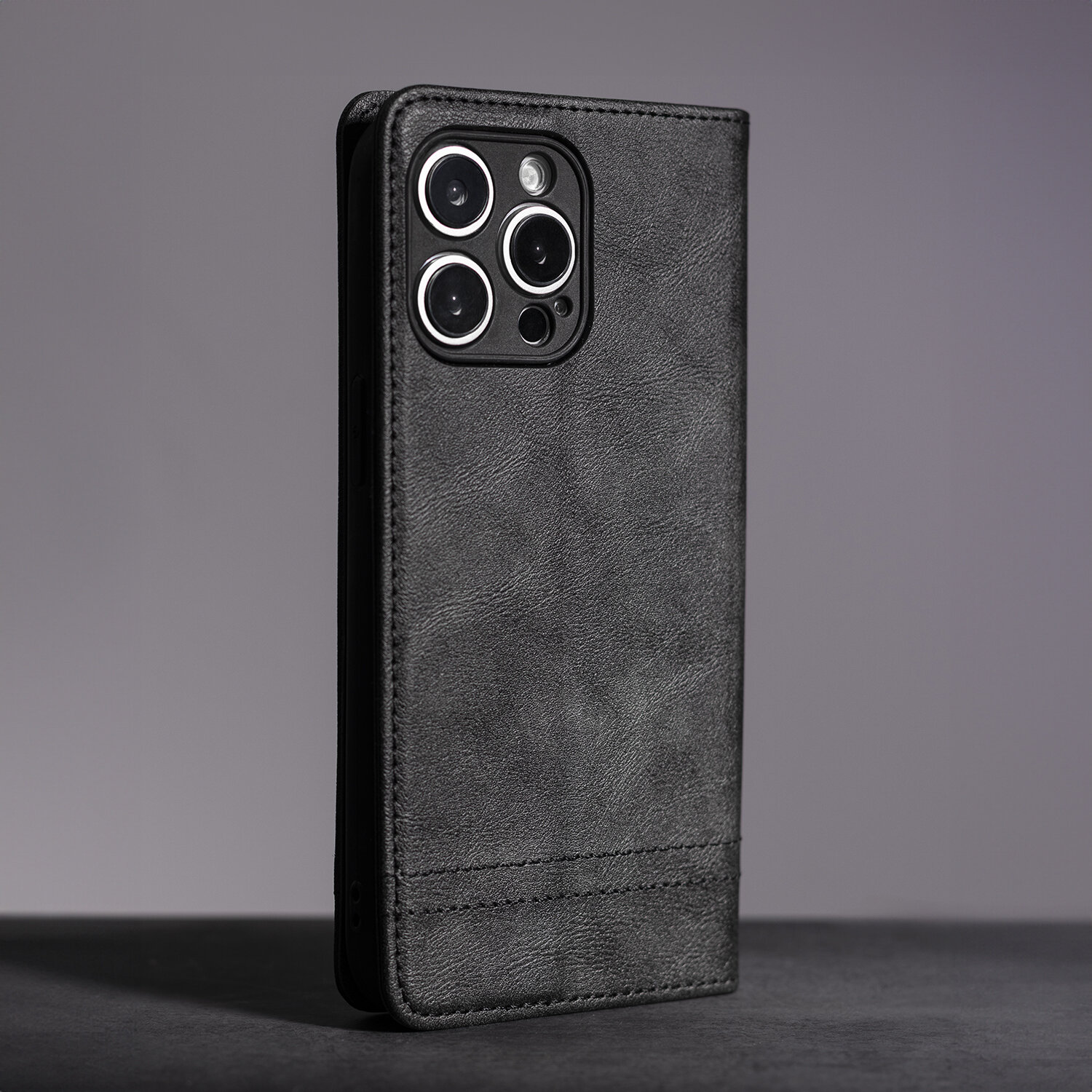 Czarne etui na telefon z widocznymi wycięciami na aparat fotograficzny, wykonane z materiału imitującego skórę.