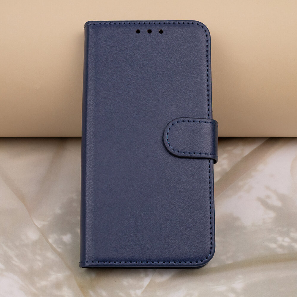 Granatowe etui na telefon z klapką, wykonane z materiału przypominającego skórę, z trzema otworami na górze i zapięciem na zatrzask.