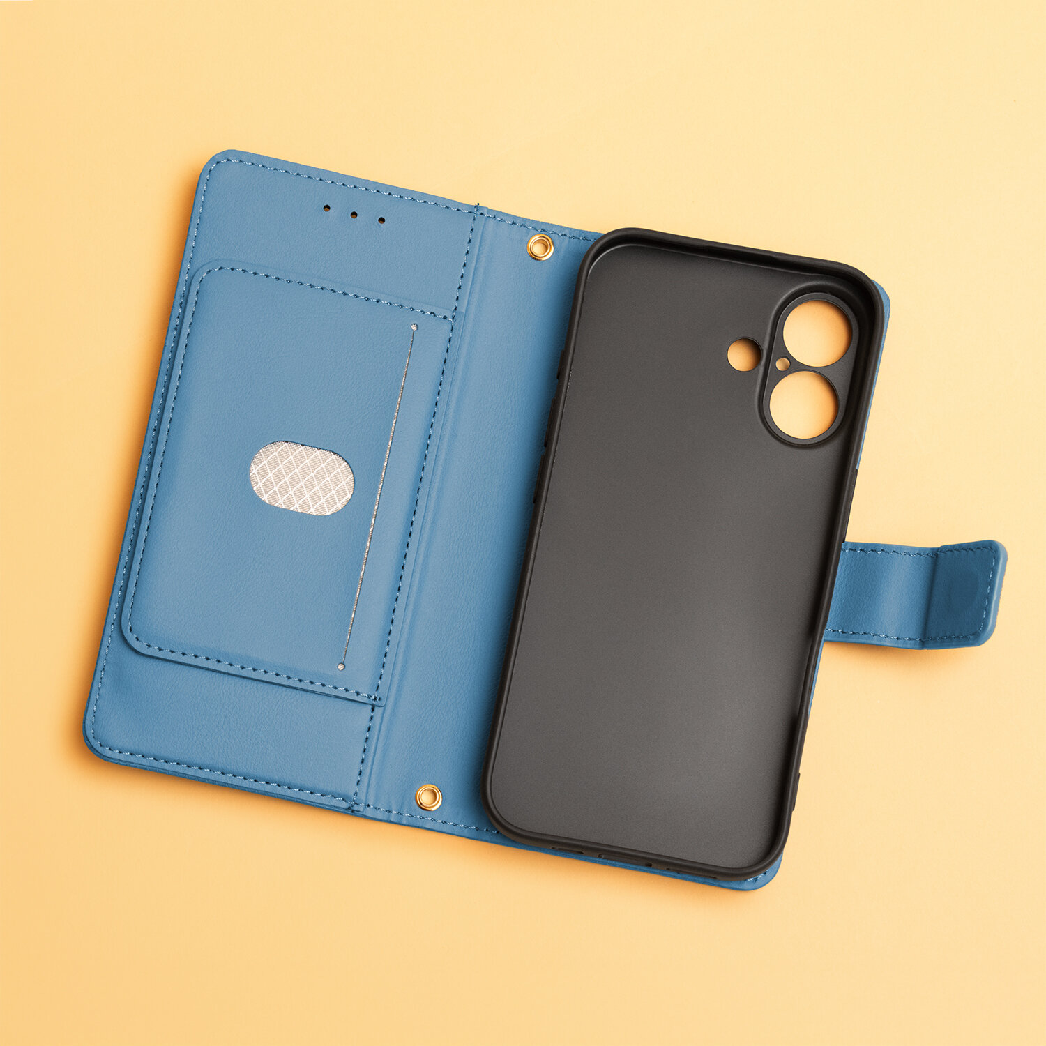 Niebieskie etui na telefon z miejscem na karty i czarną wkładką na urządzenie, leży na żółtym tle. Etui posiada zapięcie na zatrzask i otwory na aparat.