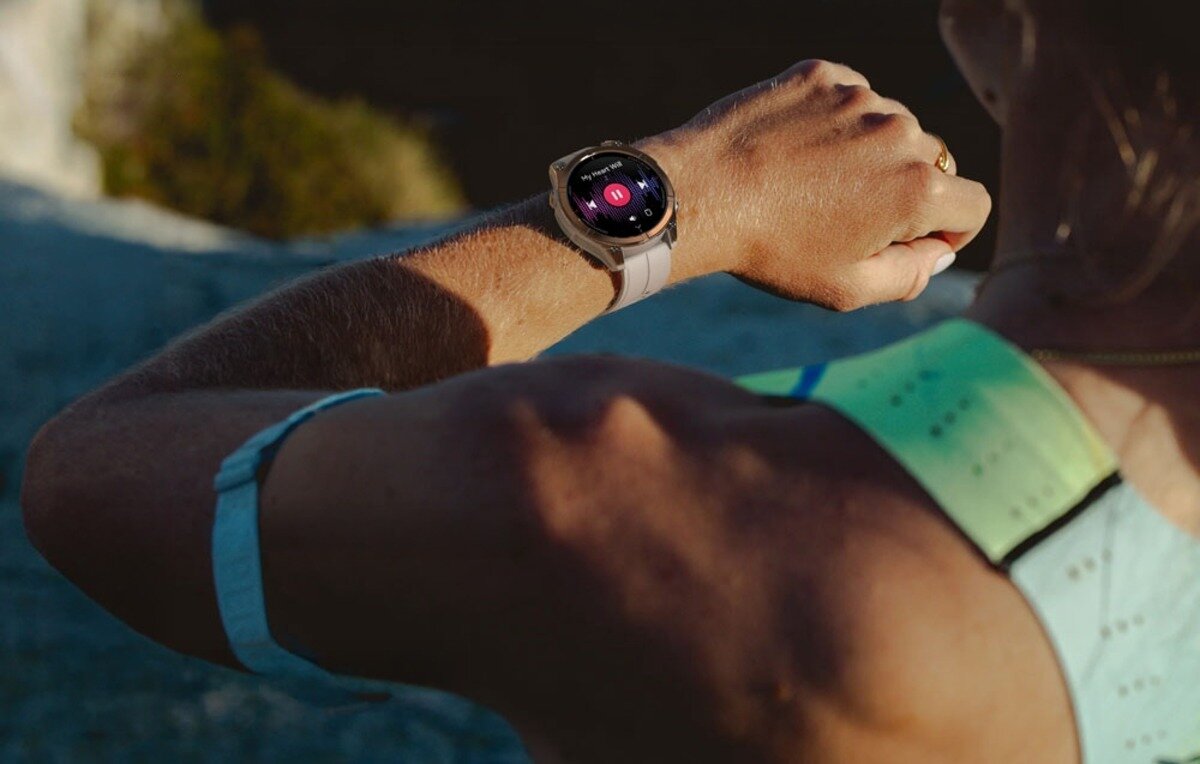 Smartwatch Zeblaze Stratos 4 Pro w wersji biało-brązowej stojący na skale w terenie pustynnym, wyświetlający zielony okrągły wskaźnik ładowania baterii na poziomie 75 procent.