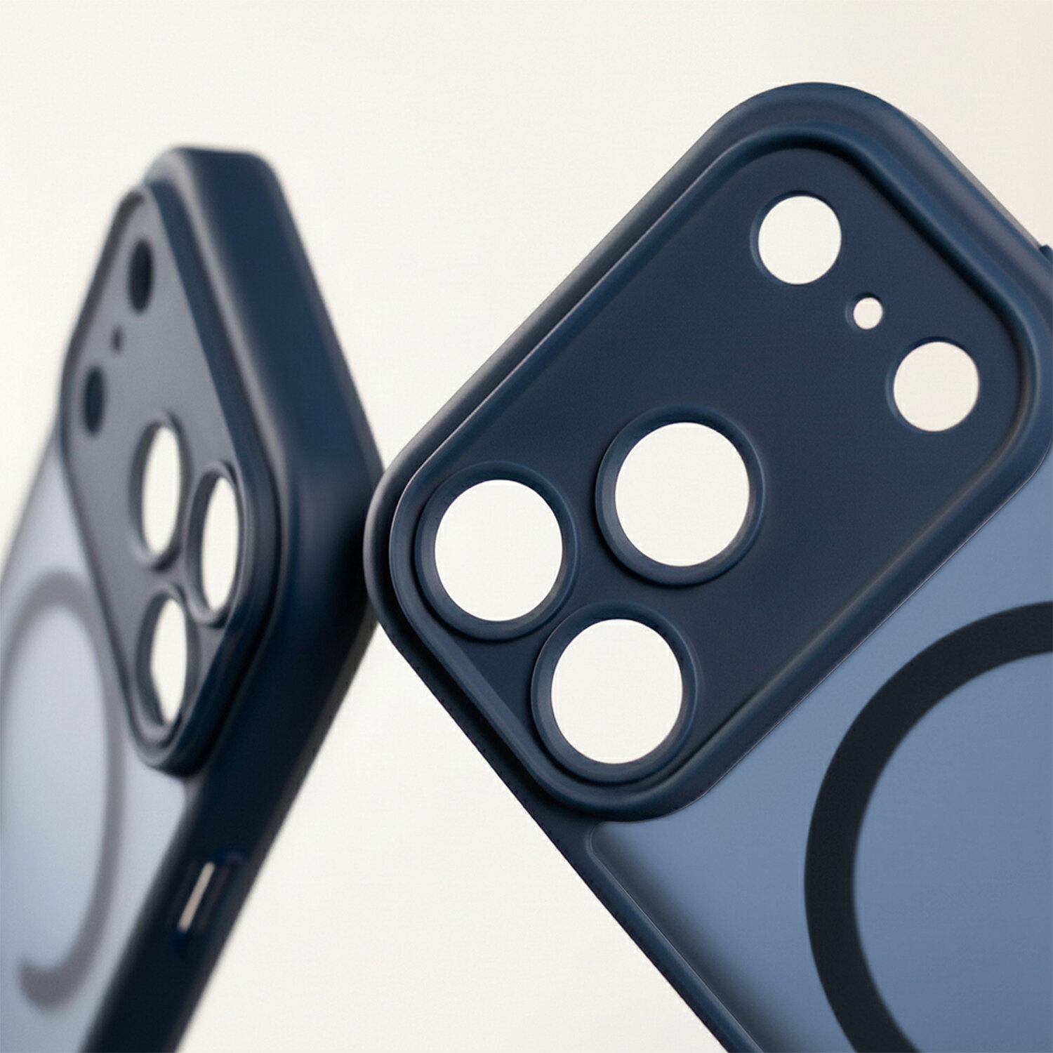 Dwa ciemnoniebieskie etui na telefon z otworami na aparat i okrągłym wzorem na tylnej części. Etui mają matowe wykończenie i są przeznaczone do ochrony aparatu.