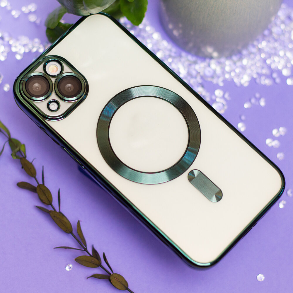 Na fioletowym tle leży telefon z białą nakładką, która ma zielony pierścień wokół aparatu i dodatkowy zielony element poniżej. W tle widoczne są dekoracyjne liście i błyszczące elementy.