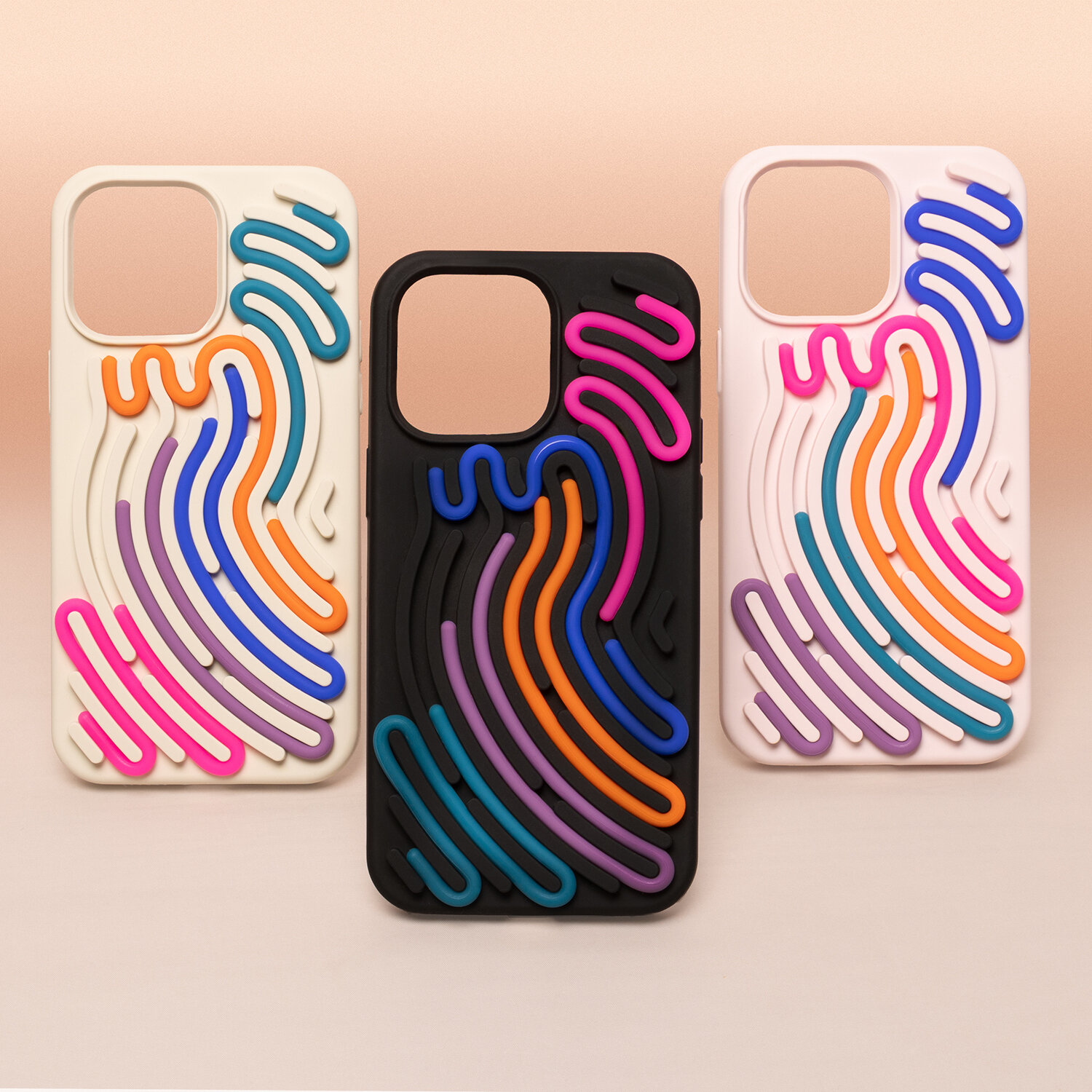 Trzy etui na telefon z kolorowymi, falistymi wzorami w różnych odcieniach, w tym różowym, pomarańczowym i niebieskim. Etui są w kolorach białym, czarnym i kremowym.