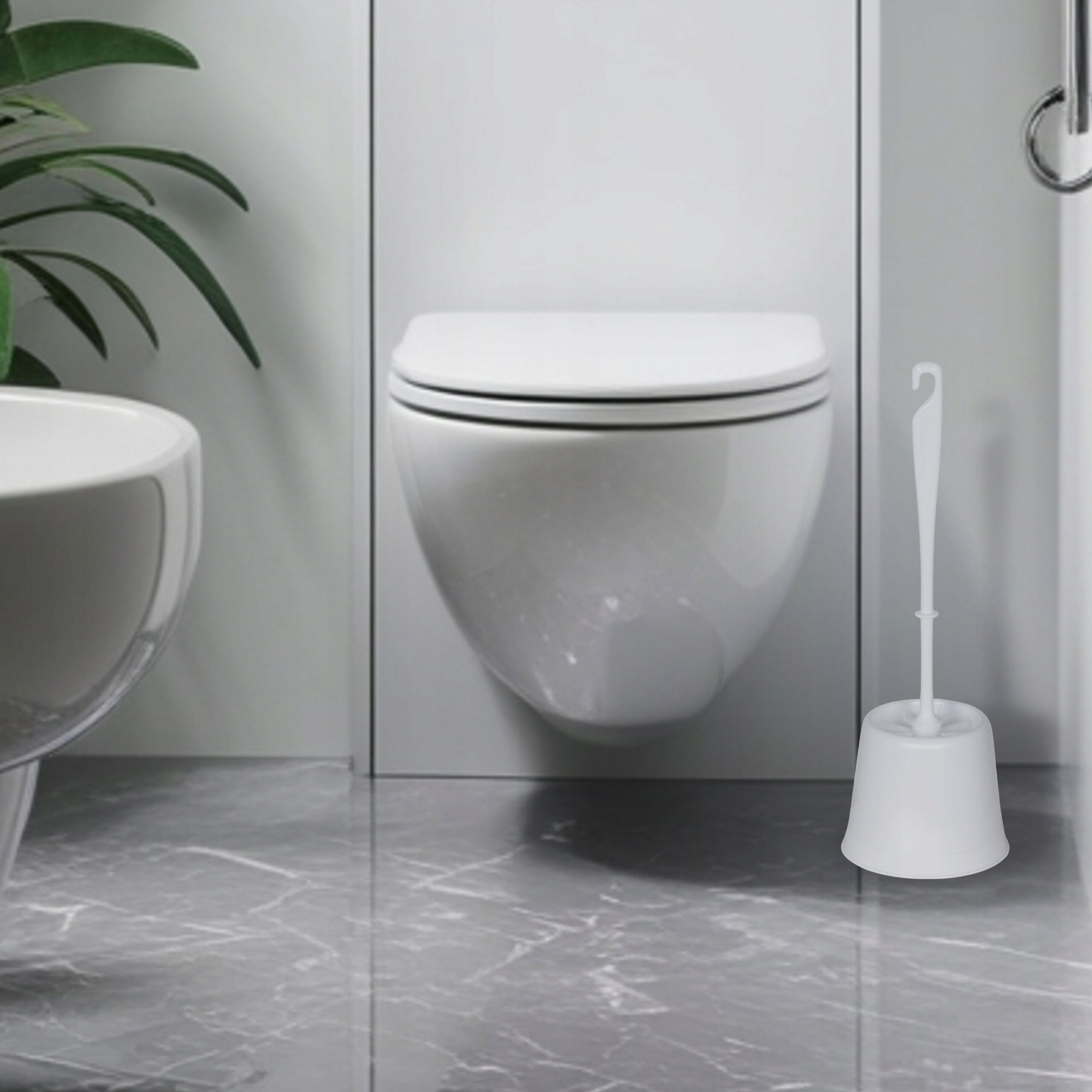 Na obrazie znajduje się biała szczotka do WC z pojemnikiem, ustawiona na marmurowej podłodze w łazience. W tle widoczna jest zawieszona toaleta oraz fragment umywalki i rośliny.