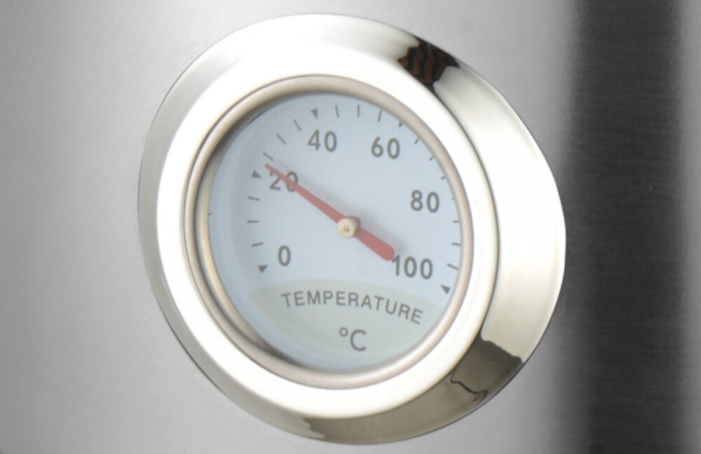 Obraz przedstawia okrągły termometr z metalową obwódką, wskazujący temperaturę w stopniach Celsjusza od 0 do 100. Na tarczy widoczny jest napis \'TEMPERATURE °C\'.