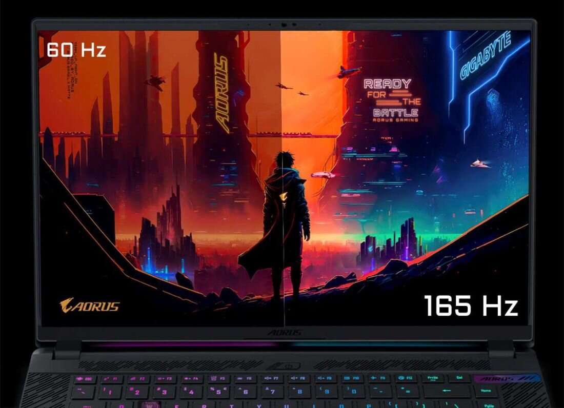 Obraz przedstawia ekran laptopa z kolorową grafiką futurystycznego miasta i postacią na pierwszym planie. Widoczne napisy to \'60 Hz\', \'AORUS\', \'READY FOR THE BATTLE\', \'165 Hz\' oraz \'GIGABYTE\'.