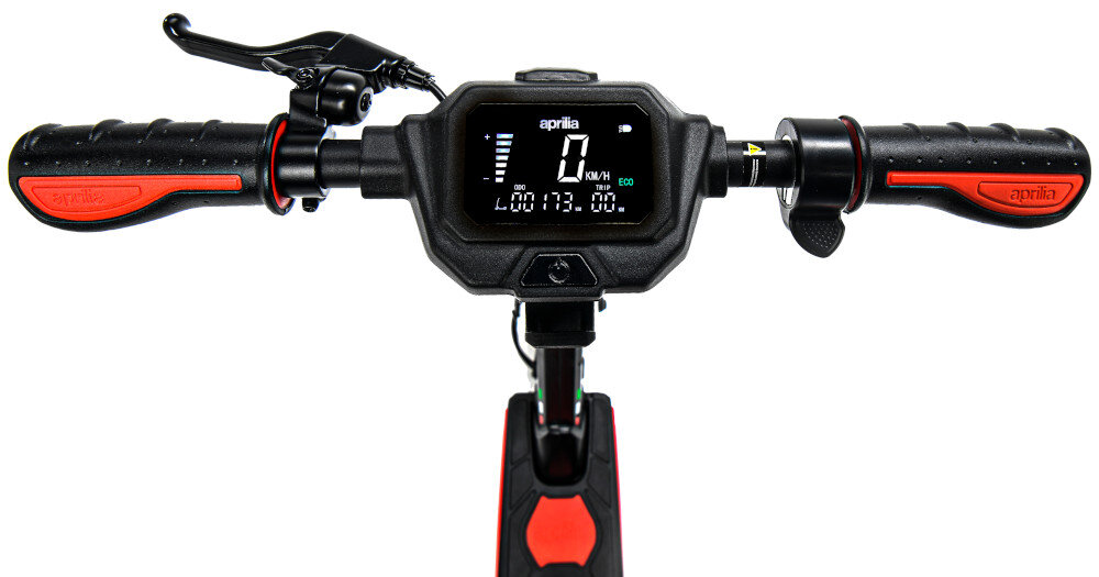Kierownica hulajnogi elektrycznej z wyświetlaczem pokazującym prędkość 0 km/h i przebieg 173 km. Na wyświetlaczu widoczne jest logo \'aprilia\'.