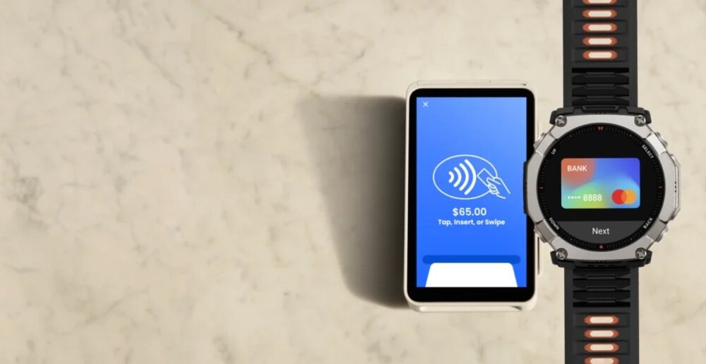 Na marmurowym tle znajduje się smartwatch z czarno-srebrną kopertą i ekranem wyświetlającym kartę płatniczą oraz telefon z niebieskim ekranem z napisem \'.00 Tap, Insert, or Swipe\'.