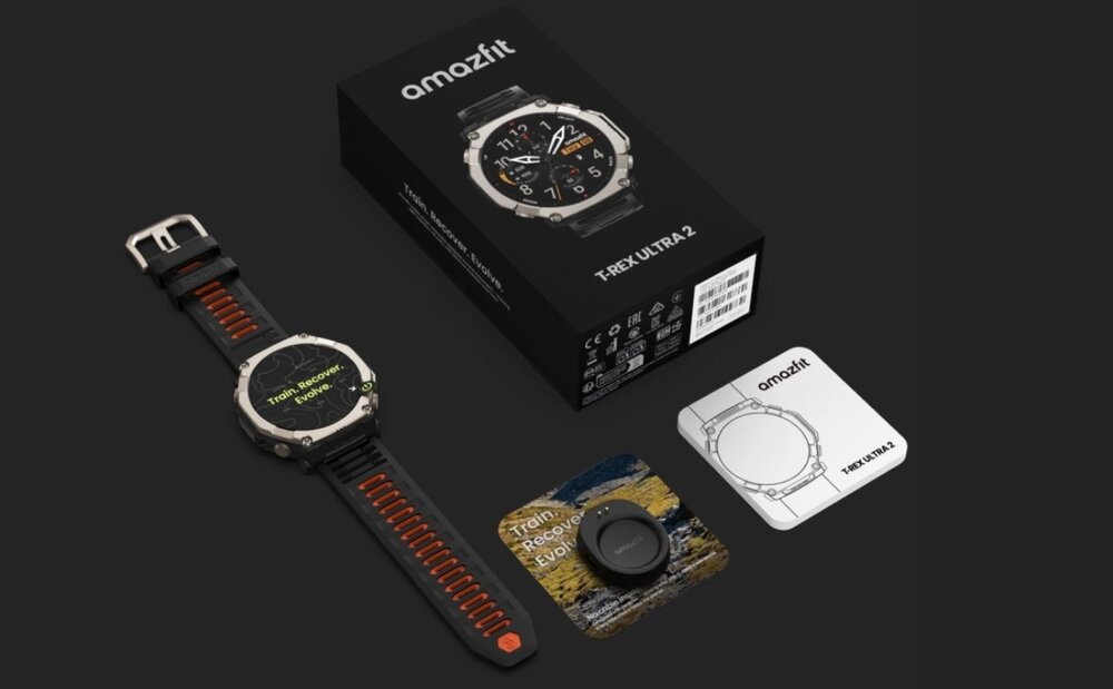 Na obrazie znajduje się smartwatch z czarno-srebrną kopertą i czarnym paskiem z pomarańczowymi akcentami, obok niego pudełko z napisem \'amazfit T-REX ULTRA 2\' oraz dodatkowe akcesoria. Na ekranie zegarka widoczny jest tekst: \'Train, Recover, Evolve\'.