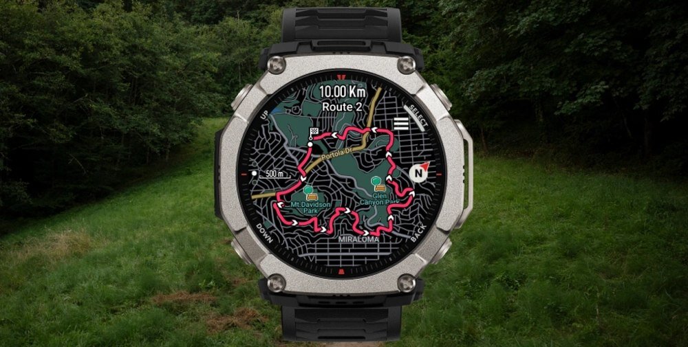 Smartwatch z okrągłym wyświetlaczem pokazuje mapę z trasą oznaczoną na czerwono oraz tekst \'10.00 Km Route 2\'. W tle widoczny jest zielony teren z drzewami.