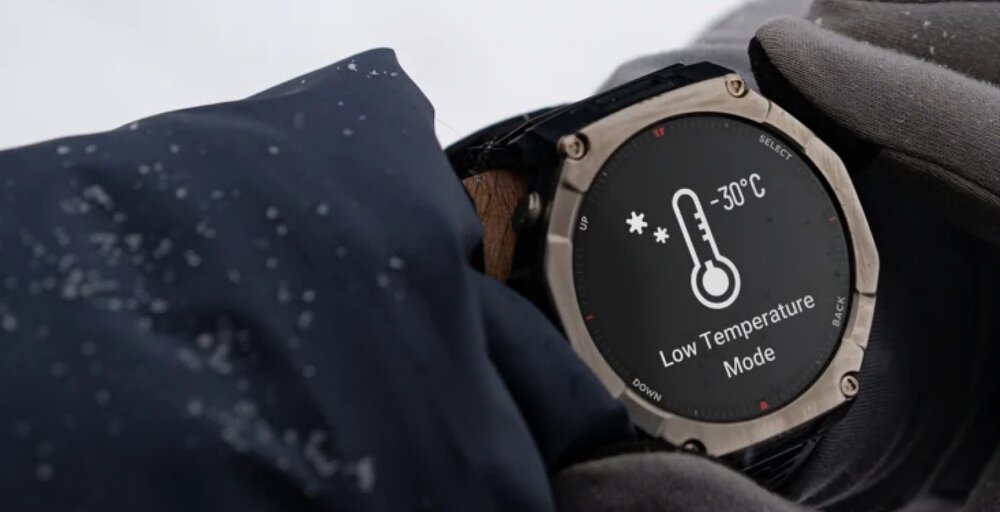 Osoba w rękawiczkach trzyma smartwatch z wyświetlaczem pokazującym ikonę termometru i tekst \'-30°C Low Temperature Mode\'.