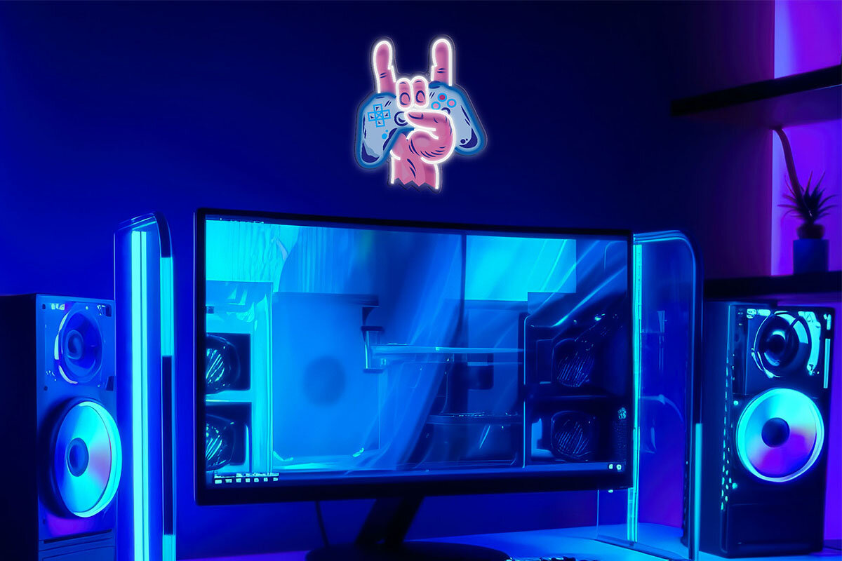 Na obrazie widać stanowisko komputerowe z dwoma podświetlanymi komputerami i monitorem, nad którym wisi neon LED w kształcie dłoni trzymającej gamepad. Całość jest utrzymana w niebiesko-fioletowej kolorystyce.