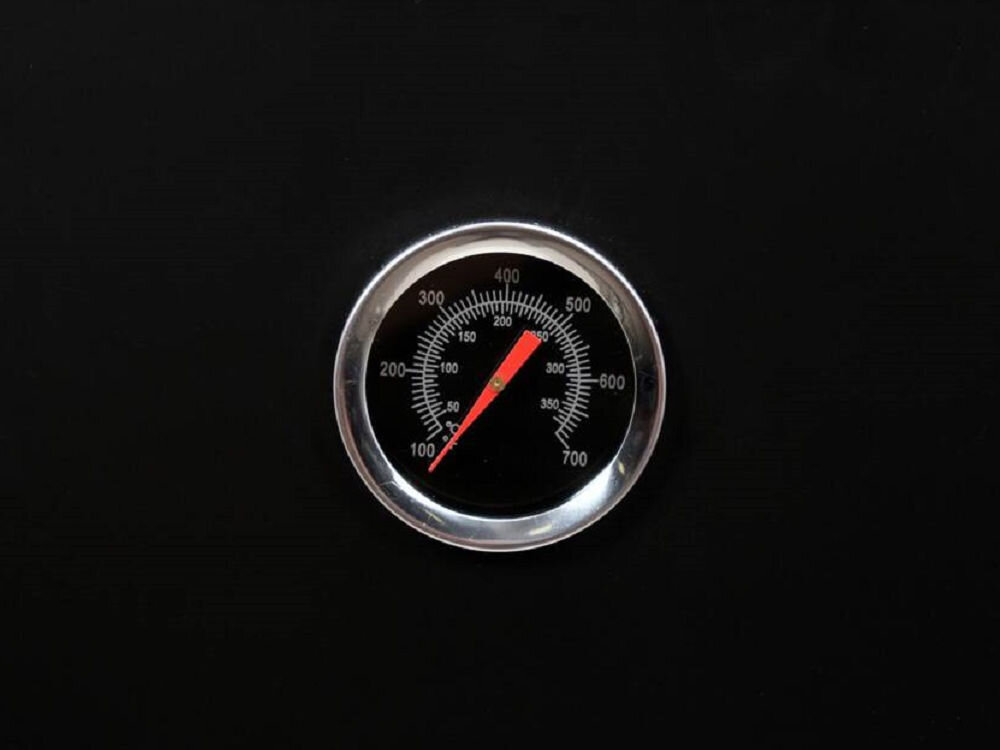Na czarnym tle znajduje się okrągły termometr z metalową obwódką, wskazujący temperaturę w zakresie od 100 do 700 stopni.