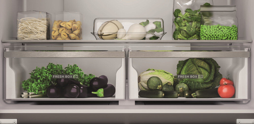 Wnętrze lodówki z widocznymi półkami i szufladami wypełnionymi warzywami i produktami spożywczymi. Na szufladach znajduje się napis \'FRESH BOX\'.