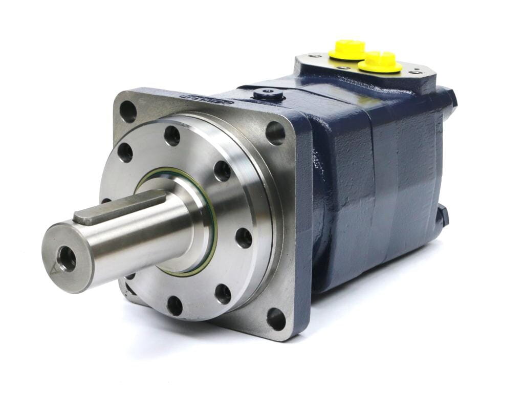 Na obrazie widoczny jest metalowy silnik hydrauliczny z cylindrycznym wałem i otworami montażowymi. Na górze znajdują się dwa żółte elementy, prawdopodobnie złącza.