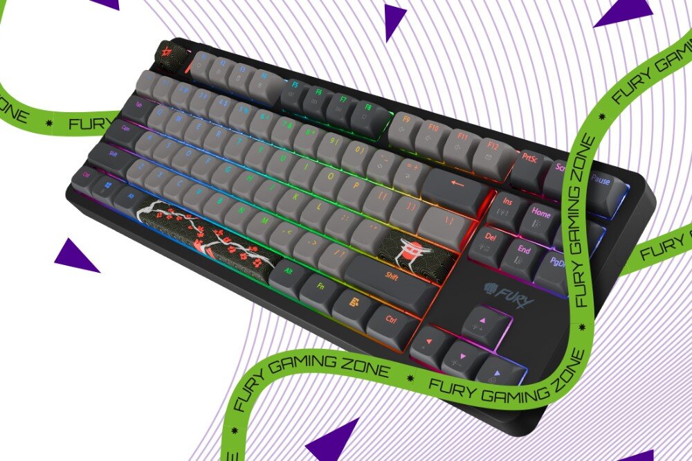 Klawiatura z podświetleniem RGB i ozdobnymi grafikami na klawiszach, z widocznym logo \'FURY\'. W tle znajdują się zielone taśmy z napisem \'FURY GAMING ZONE\' oraz fioletowe trójkąty na białym tle z liniami.