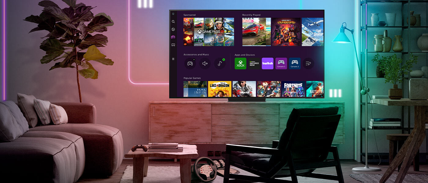Telewizor Samsung OLED S95C współpracuje z konsolami i PC W salonie znajduje się duży telewizor wyświetlający interfejs z grami i aplikacjami. W pomieszczeniu panuje przytulna atmosfera z nowoczesnym oświetleniem i rośliną w doniczce.