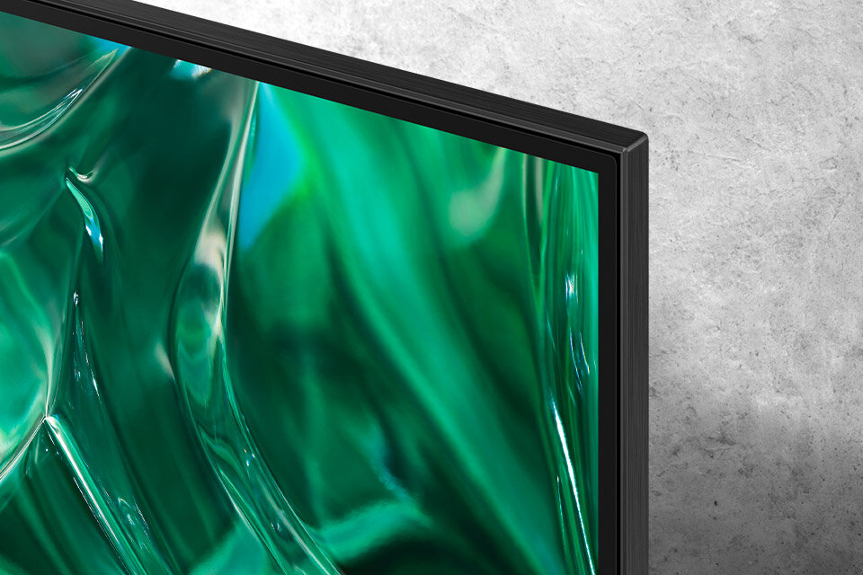 Zbliżenie na róg ekranu telewizora z wyświetlanym abstrakcyjnym wzorem w odcieniach zieleni. Obudowa telewizora jest cienka i ma ciemny kolor.