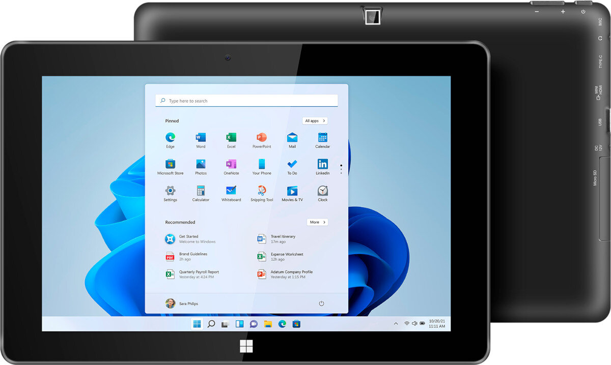 Na obrazie widoczny jest tablet z wyświetlonym ekranem startowym systemu Windows, z ikonami aplikacji takimi jak Edge, Excel, PowerPoint i inne. W tle znajduje się tył urządzenia z widocznymi przyciskami i portami.