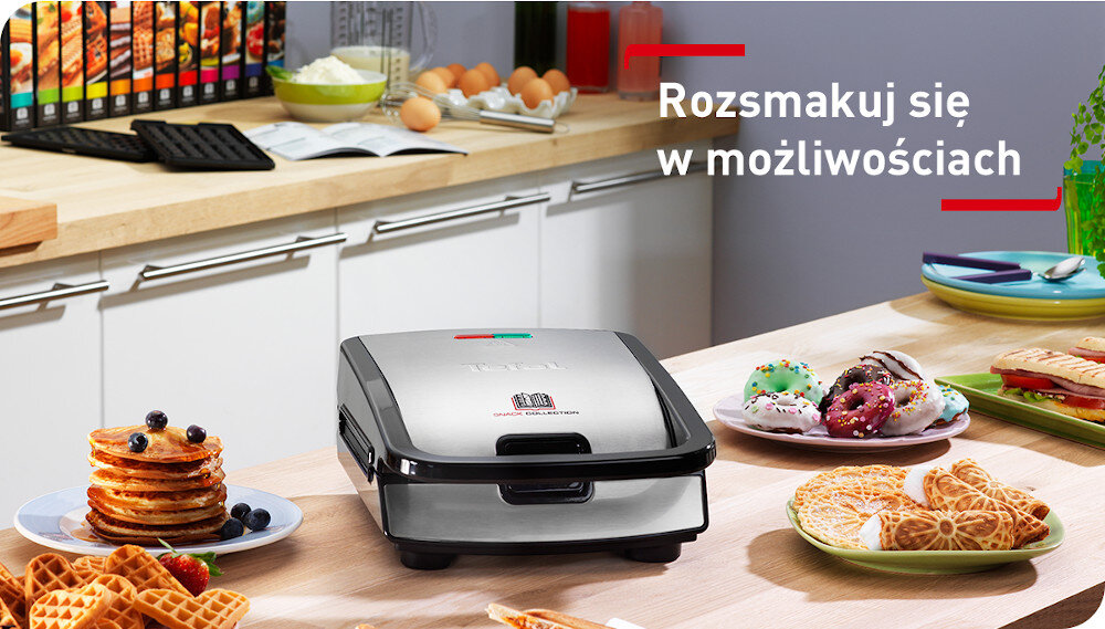 Na blacie kuchennym znajduje się opiekacz z logo TEFAL, otoczony różnorodnymi potrawami, takimi jak gofry i naleśniki. W tle widoczny jest napis \'Rozsmakuj się w możliwościach\'.