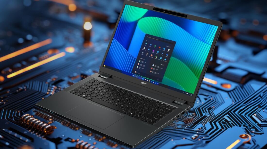 Laptop z otwartym ekranem wyświetlającym pulpit systemu Windows, umieszczony na tle przypominającym płytę główną. Na obudowie widoczne jest logo \'acer\'.