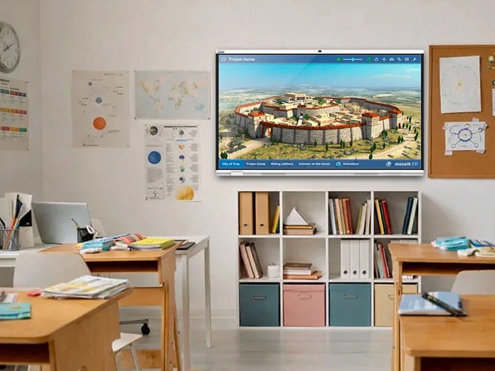 Monitor PRESTIGIO SOLUTIONS PSMB018R860 Sala lekcyjna z ławkami i regałem, na której ścianie wisi duży ekran interaktywny z wyświetloną trójwymiarową wizualizacją starożytnego grodu