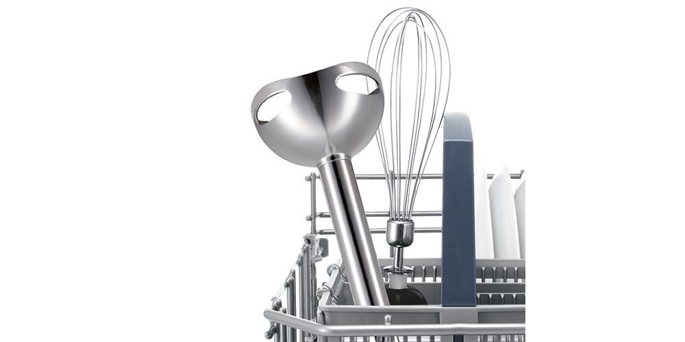 Na obrazie widoczny jest metalowy blender ręczny z trzepaczką umieszczony w koszu zmywarki. Blender ma metalową stopę i znajduje się obok innych przyborów kuchennych.