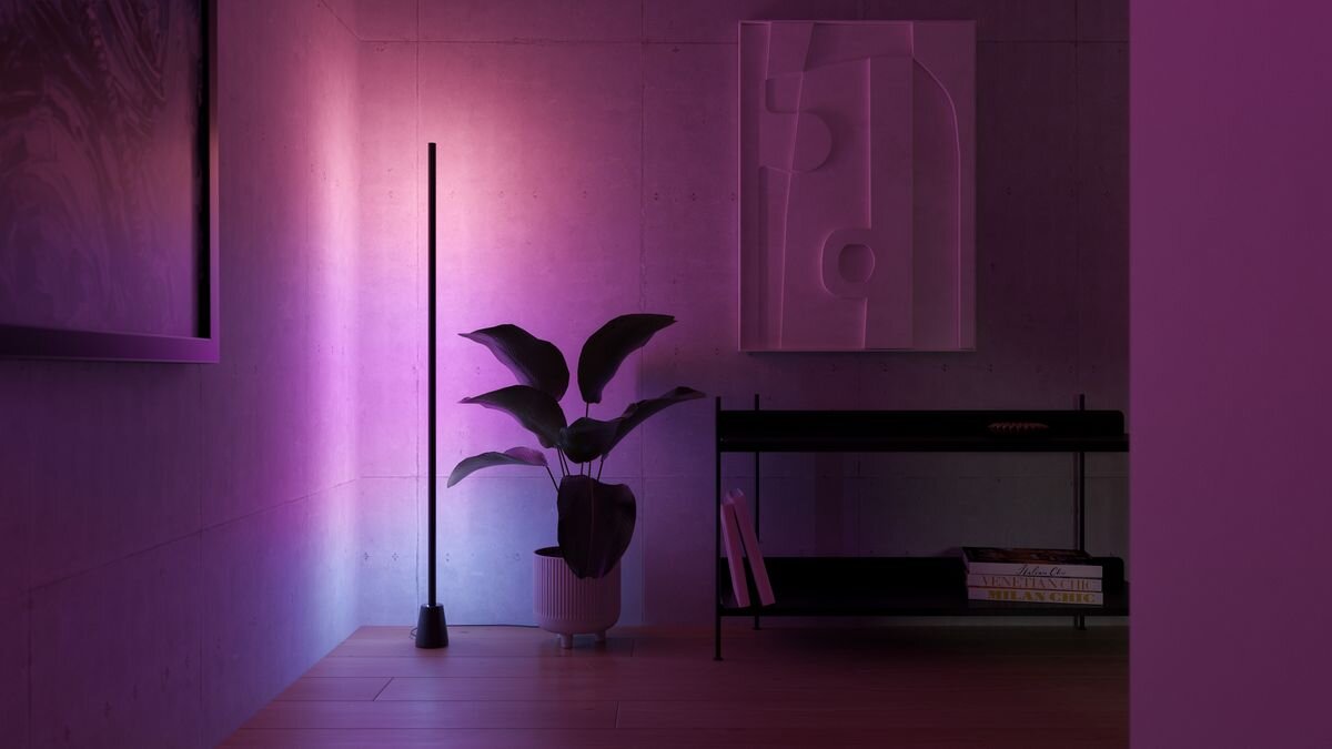 Lampa PHILIPS HUE Play 929004321101 Bluetooth, Zigbee, muzyka, głos, atmosfera, rozrywka, Minimalistyczna lampa podłogowa w rogu obok rośliny.