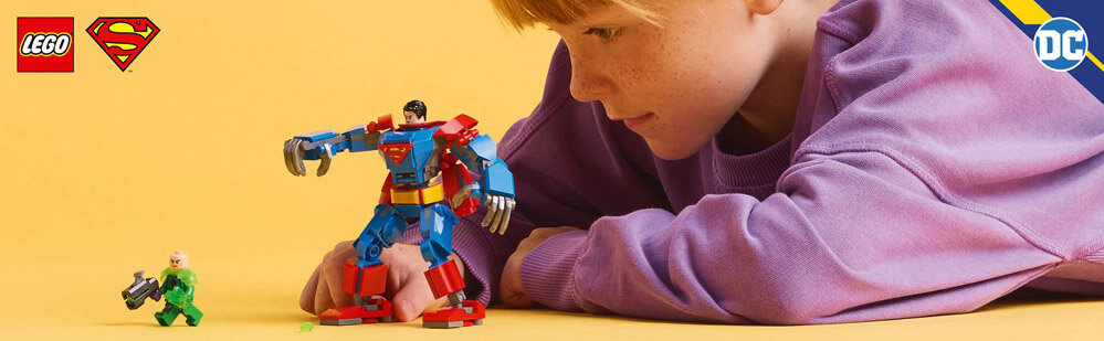 Na żółtym tle znajduje się dziecko w fioletowej bluzie, które patrzy na figurki LEGO przedstawiające Supermana i Lex Luthora. W lewym górnym rogu widoczne są loga LEGO i Supermana, a w prawym górnym rogu logo DC.