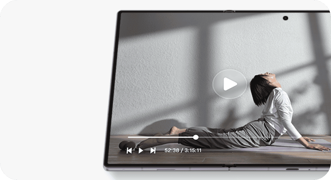 Film z ćwiczeniami jogi odtwarzany na rozłożonym ekranie Galaxy Z Fold8. Na ekranie smartfona wyświetlany jest film z osobą wykonującą ćwiczenia jogi. Widoczne są przyciski odtwarzania oraz pasek postępu z czasem 52:38 / 3:15:11.