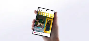 Ekran zewnętrzny Galaxy Z Fold8 ma proporcje 10:16, a ekran główny 4:3. Osoba trzyma smartfon z wyświetlonym zdjęciem kolorowego budynku z rowerem przed nim. Na ekranie widoczne są ikony interakcji społecznościowych.
