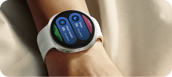 Galaxy Watch na nadgarstku wyświetla dane o tętnie, stresie i śnie. Na zdjęciu widoczny jest smartwatch z białym paskiem na nadgarstku, z wyświetlaczem pokazującym dane dotyczące kroków i zdrowia serca. Ekran pokazuje: \'Steps 95 Excellent\' oraz \'Heart Health 95 Excellent\'.