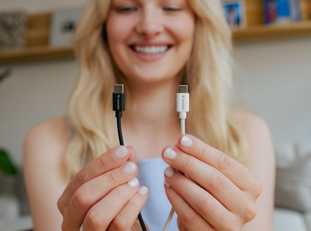 Osoba trzyma dwa kable USB-C, jeden czarny i jeden biały, z logo \'Verbatim\' na wtyczkach.