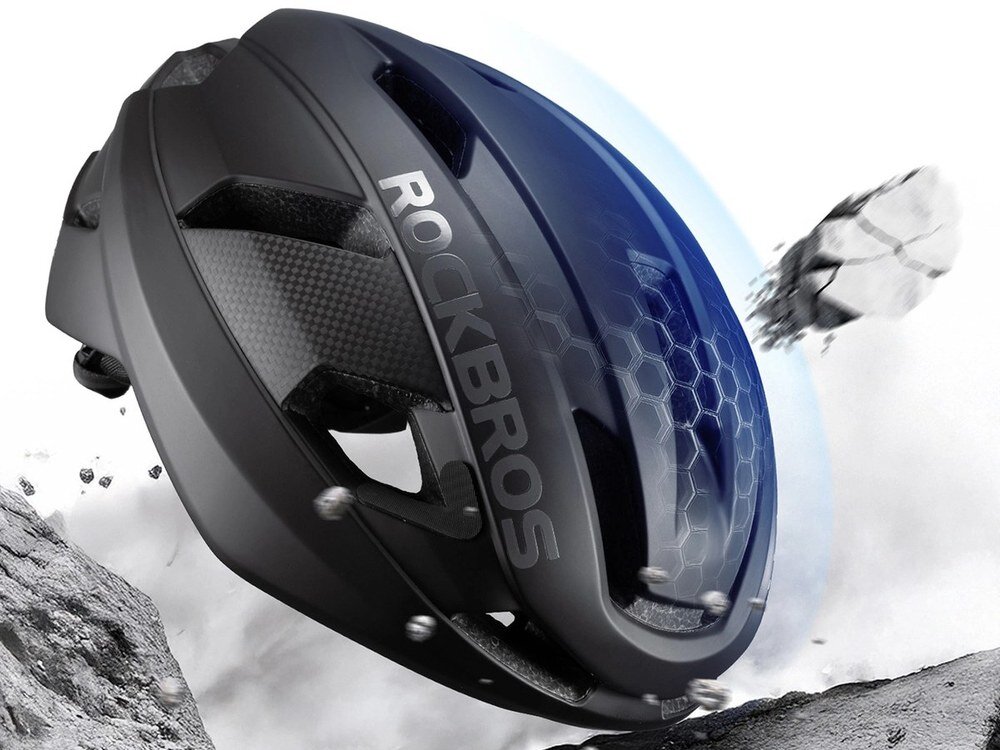 Czarny kask rowerowy Rockbros LK-15 widziany z góry i z tyłu, z widocznymi otworami wentylacyjnymi i teksturą skorupy, w tle rozmyta zieleń.