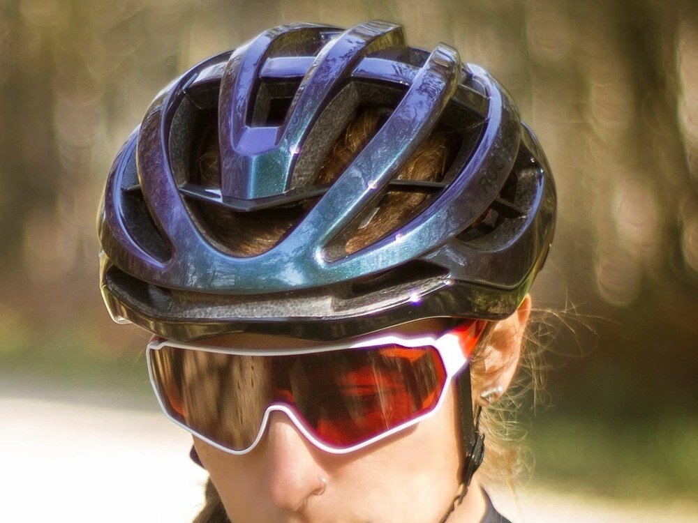 Kask Rockbros HC-58C-L w kolorze niebieskiego kameleonu widziany z przodu na głowie kobiety, z wyraźnymi otworami wentylacyjnymi i połyskliwą powierzchnią muszli.