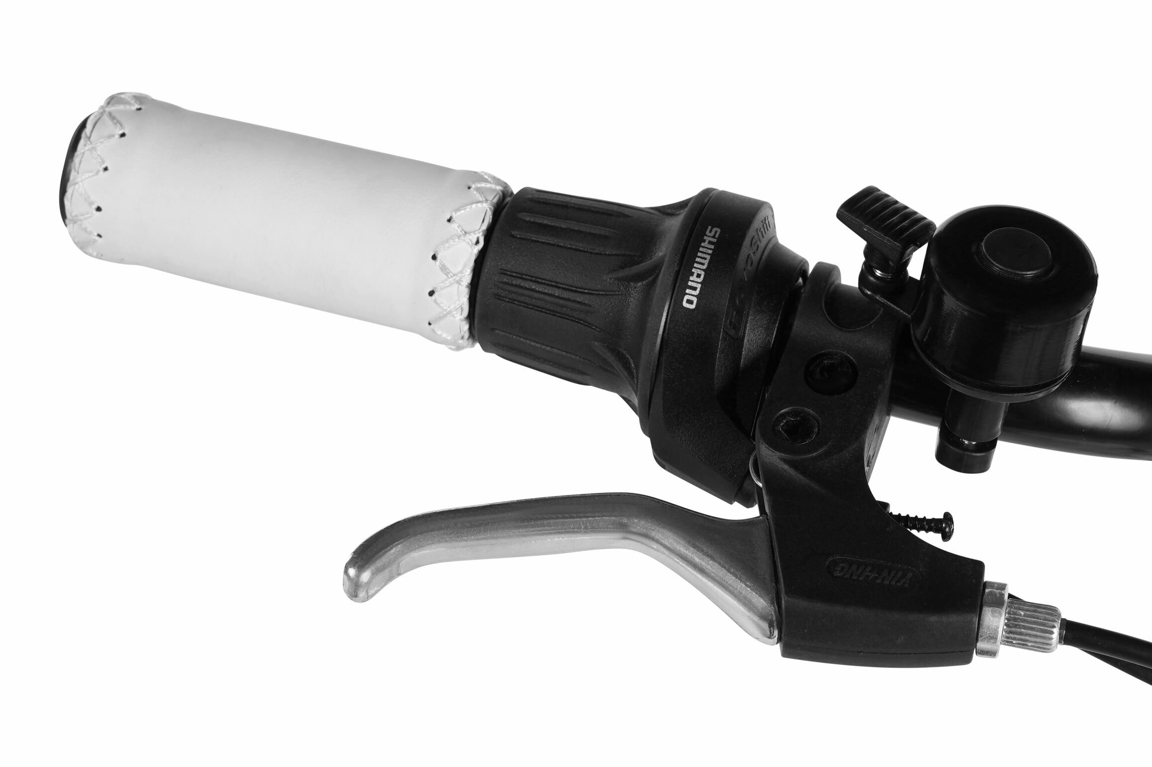 Zbliżenie na uchwyt rowerowy z białą rączką, czarną manetką z napisem \'SHIMANO\' oraz dzwonkiem. Widoczna jest także dźwignia hamulca.