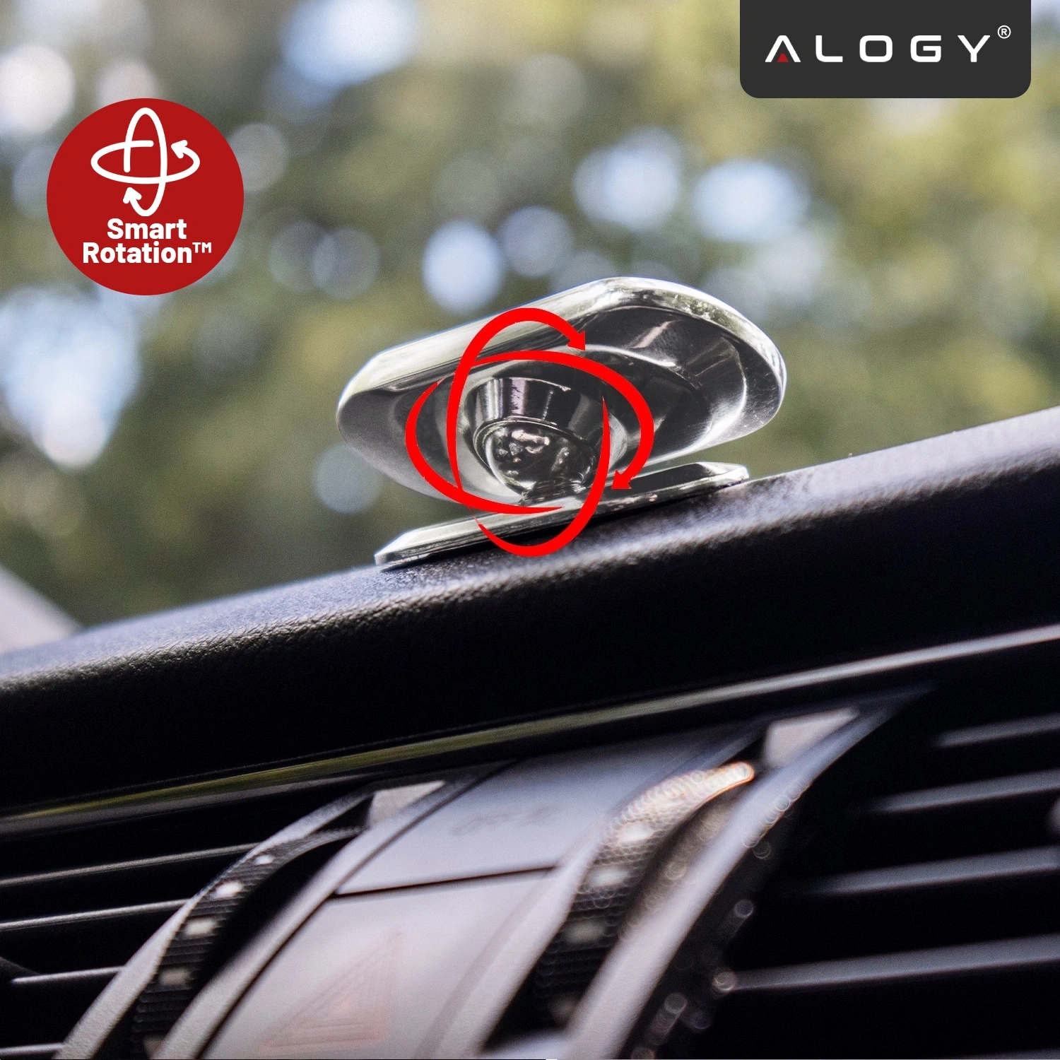 Na obrazie widoczny jest srebrny uchwyt magnetyczny do telefonu zamontowany na desce rozdzielczej samochodu. W lewym górnym rogu znajduje się czerwone logo z napisem \'Smart Rotation™\', a w prawym górnym rogu logo \'ALOGY\'.