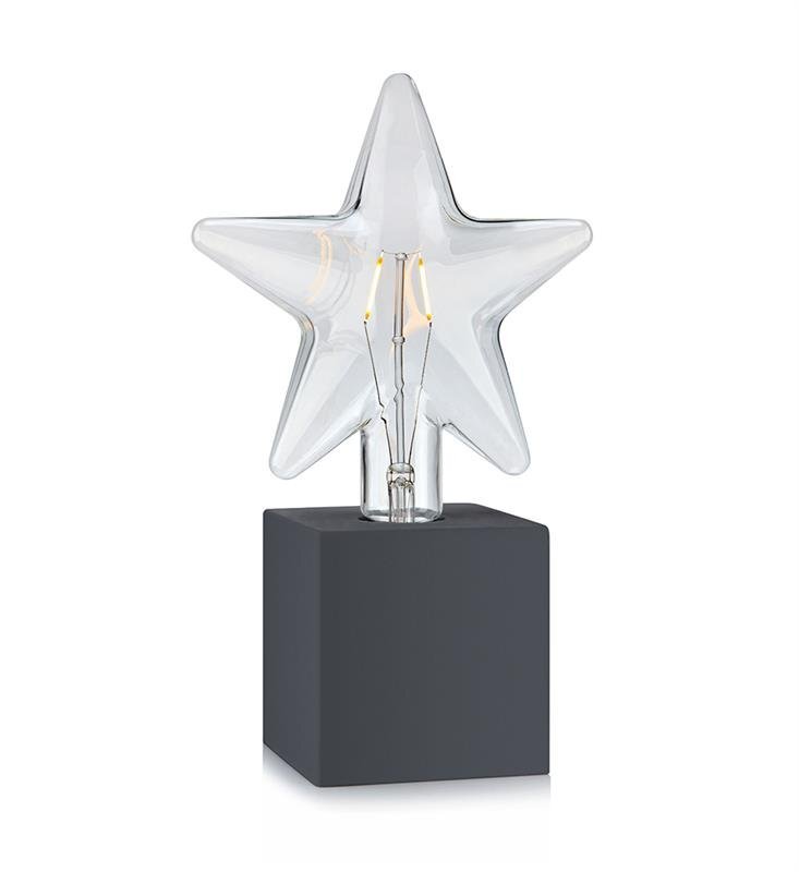 Szklana lampa w kształcie gwiazdy umieszczona na czarnym, kwadratowym postumencie. Wewnątrz gwiazdy widoczne są elementy żarówki.