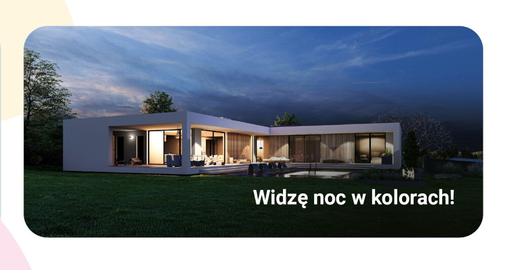 Nowoczesny dom z dużymi oknami oświetlony w nocy, na tle ciemnego nieba. Na obrazie widoczny jest tekst: \'Widzę noc w kolorach!\'.