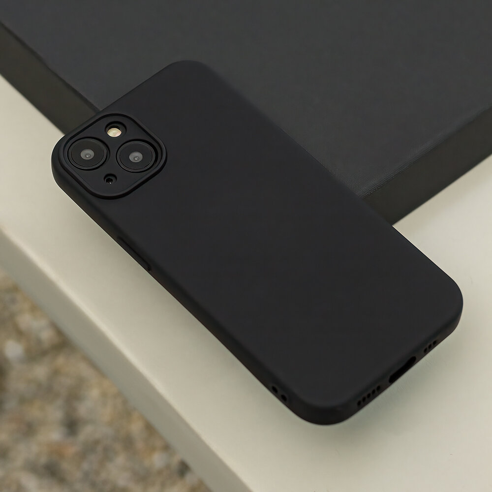 Czarna nakładka silikonowa na smartfon z widocznymi otworami na aparat i lampę błyskową. Produkt leży na jasnej powierzchni obok ciemnego pudełka.